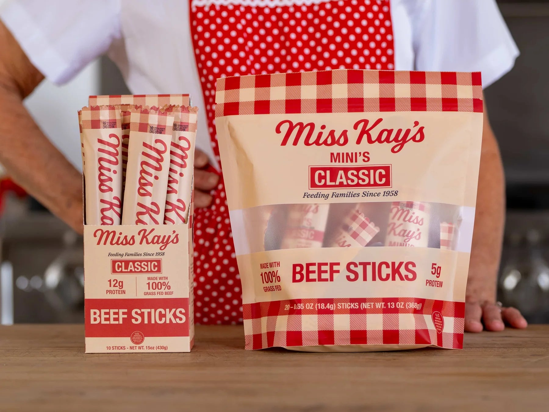 A Miss Kay's Classic beef sticks box and a Classic Mini bag side by side on a wooden kitchen counter