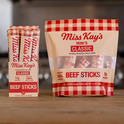 The Miss Kay's Family Bundle: a Classic beef sticks box and a Classic Mini bag together on a wooden counter