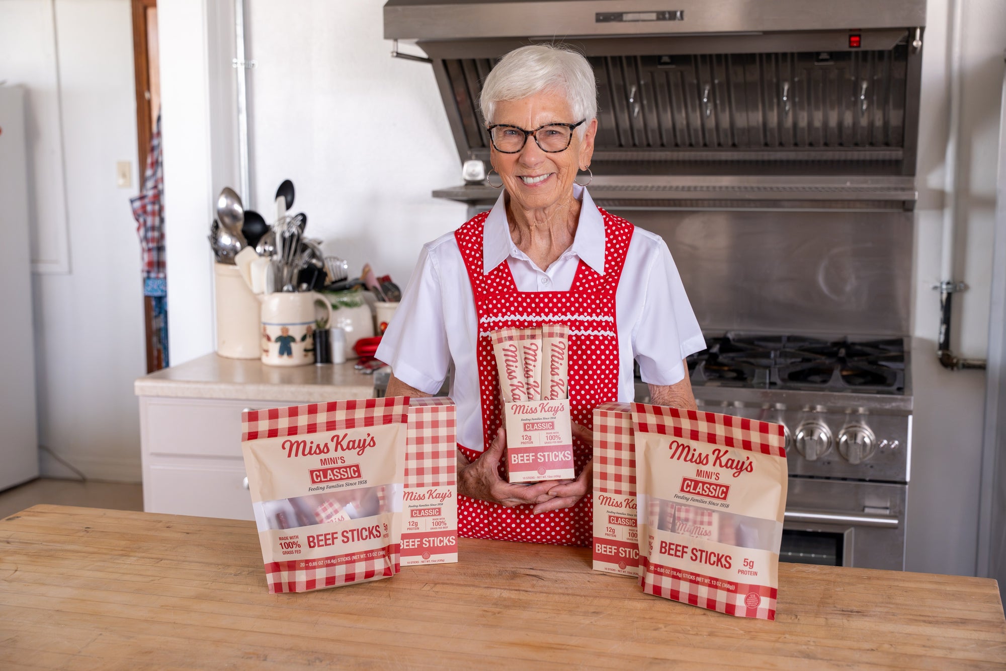 Miss Kay in her kitchen with boxes of her beef sticks on the counter