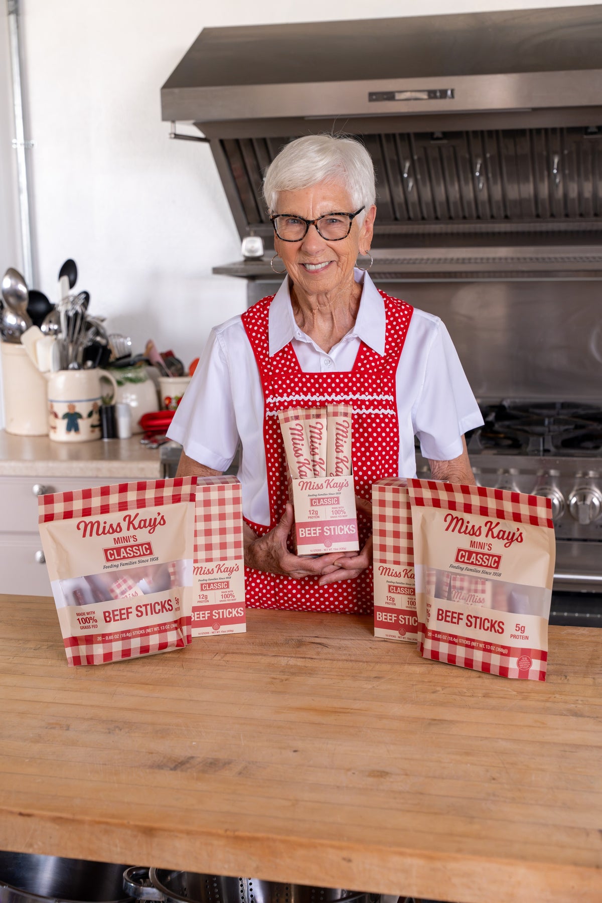 Miss Kay behind a row of her beef stick boxes in the kitchen